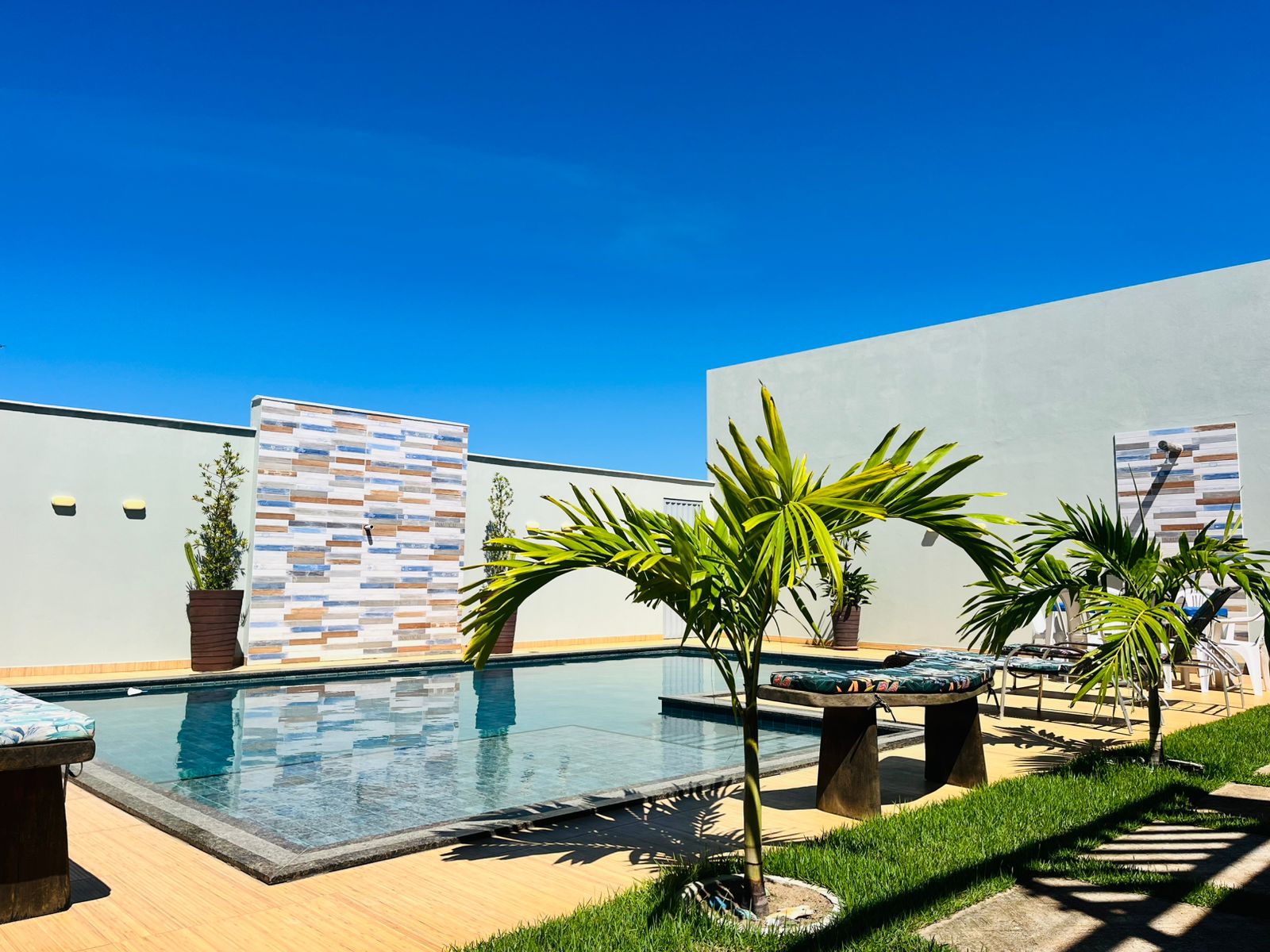 Piscina com plantas, espreguiçadeiras e céu azul